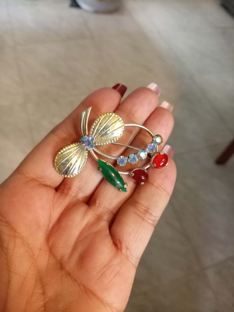 Vintage Brooch Pin Rhinestone Fruit Design (Category: Brooches) located in General Mariano Alvarez. Submitted by ma.miafajardo1219 (Listing ID 1470321542, Image 3). Description: - Lot of 2 vintage brooches with secure, working pin closures - Brooch 1: Amber-toned teardrop stones set in an open teardrop metal frame - Brooch 2: Charming bow top featuring a green marquise leaf, red cabochons, and sparkling aurora borealis rhinestones - Metal shows m