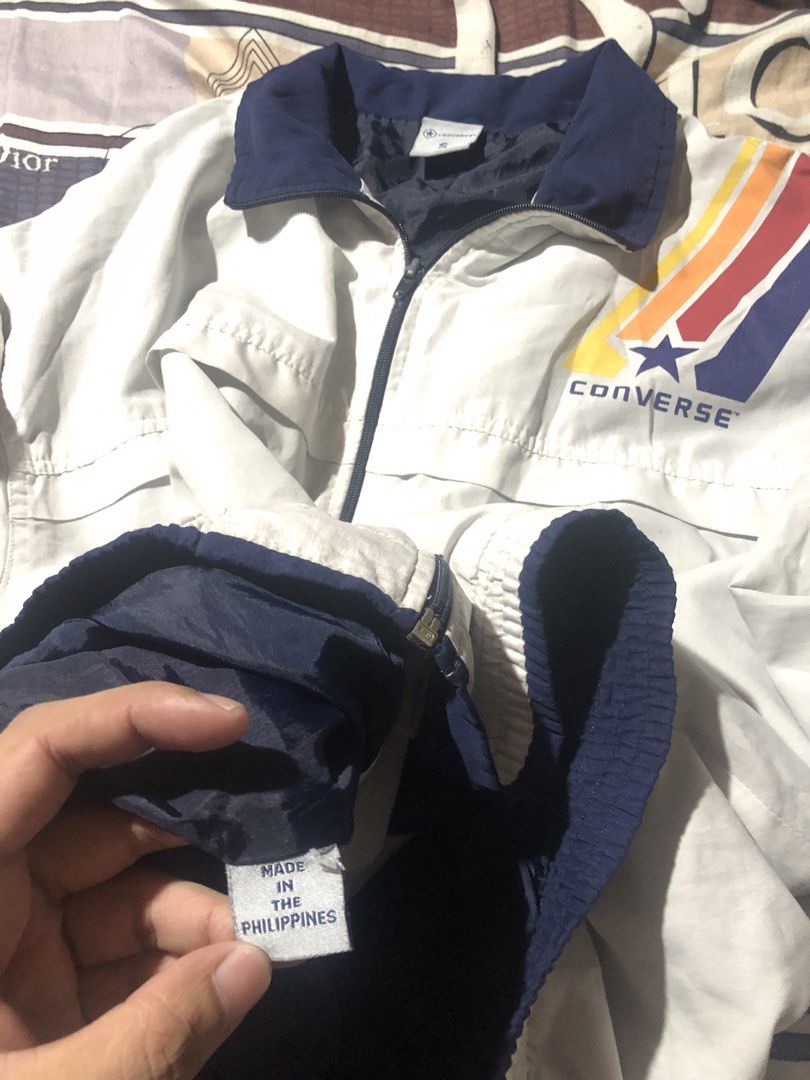 Vintage Converse White Retro Windbreaker Jacket Size S (Category: Coats, Jackets and Outerwear) located in Manila. Submitted by bakithrift213 (Listing ID 1470261005, Image 3). Description: - Brand: Converse - Color: White with navy blue collar, cuffs, and hem - Design: Retro multi-colored rainbow stripe logo on the chest - Closure: Full zip - Size: Small - Material: Lightweight, ideal for layering - Origin: Made in the Philippines.