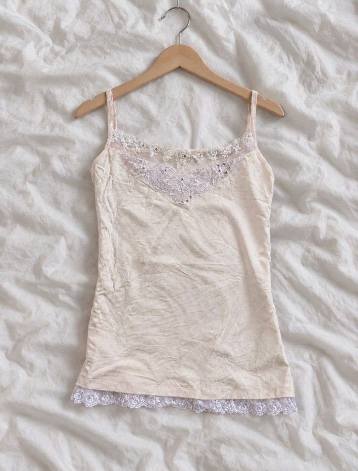 Vintage Lace Camisole Tops (Category: Others Tops) located in Manila. Submitted by itgirl.archive (Listing ID 1470220635, Image 1). Description: - xs to s💕🪽 - Color: Beige with lace - Material: Soft cotton blend - Design: White lace trim, sheer mesh chest panel with butterfly embroidery and rhinestones - Features: Thin adjustable straps - Style: Romantic fairycore basic, great for layering - Condition: Excellent.