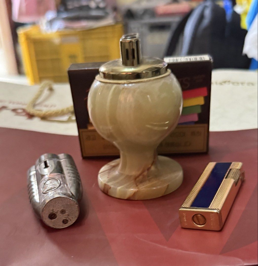 Vintage Lighters Assorted Lot with Table Lighter (Category: Vintage Collectibles) located in Mandaue City. Submitted by erin_grace (Listing ID 1470166458, Image 2). Description: - Lighter collection bundle set for sale - Marble-style table lighter with elegant brass top - Metallic torch lighter featuring a convenient flip cap - Slim gold-tone pocket lighter with a chic navy blue stripe - Bonus: Unopened pack of Nat Sherman Fantasia Lights cigaret