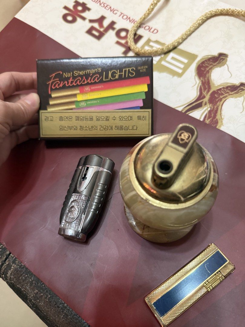 Vintage Lighters Assorted Lot with Table Lighter (Category: Vintage Collectibles) located in Mandaue City. Submitted by erin_grace (Listing ID 1470166458, Image 3). Description: - Lighter collection bundle set for sale - Marble-style table lighter with elegant brass top - Metallic torch lighter featuring a convenient flip cap - Slim gold-tone pocket lighter with a chic navy blue stripe - Bonus: Unopened pack of Nat Sherman Fantasia Lights cigaret