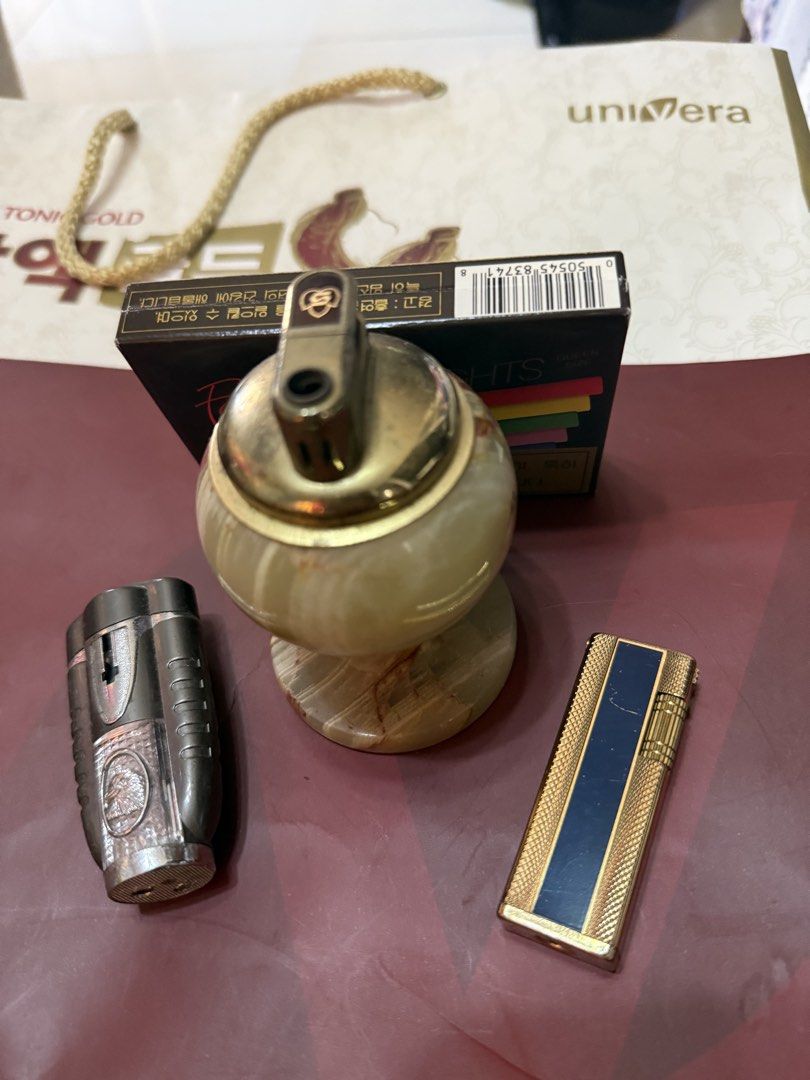 Vintage Lighters Assorted Lot with Table Lighter (Category: Vintage Collectibles) located in Mandaue City. Submitted by erin_grace (Listing ID 1470166458, Image 1). Description: - Lighter collection bundle set for sale - Marble-style table lighter with elegant brass top - Metallic torch lighter featuring a convenient flip cap - Slim gold-tone pocket lighter with a chic navy blue stripe - Bonus: Unopened pack of Nat Sherman Fantasia Lights cigaret