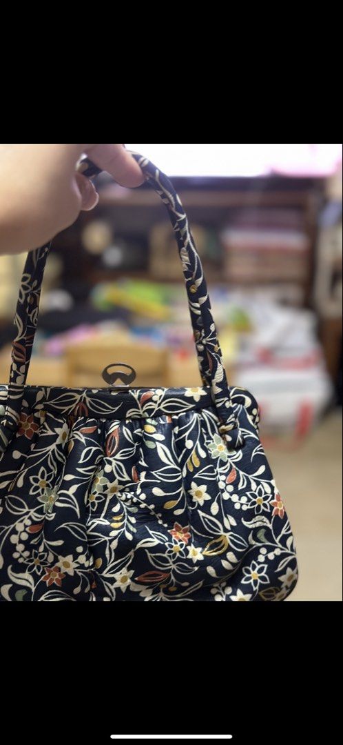 Vintage style floral pattern handbag purse with clasp (Category: Purses & Pouches) located in Mandaue City. Submitted by erin_grace (Listing ID 1470164497, Image 3). Description: - Color & Pattern: Navy blue with a vibrant white and orange floral botanical print - Design: Soft pleated body with a neat structured frame - Strap: Single shoulder strap with cute knotted details - Closure: Unique metal top clasp with a modern cutout loop design - Inte