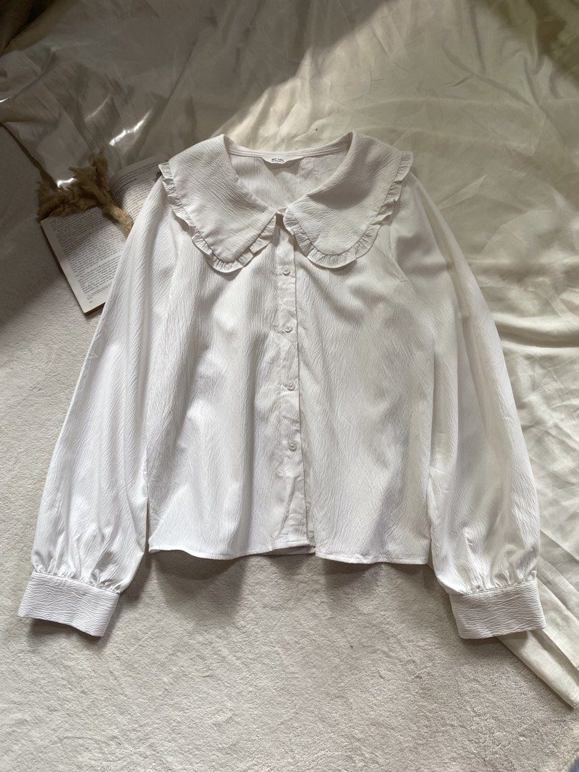 White Blouse with Ruffle Collar and Long Sleeves Medium 38 (Category: Blouses) located in Poro. Submitted by joyceyuu (Listing ID 1470185017, Image 1). Description: - Color: White - Style: Button-down blouse with a large rounded ruffle collar - Sleeves: Long balloon sleeves with fitted cuffs - Fabric: Light, textured material with subtle vertical patterns - Versatility: Classic piece that easily pairs with skirts or trousers - Occasion: Perfect f