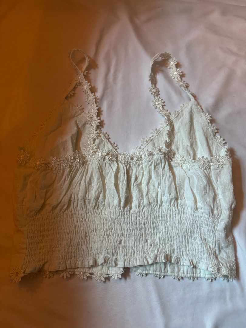 White Daisy Lace Trim Button Up Crop Top fits S-M (Category: Sleeveless) located in Cebu City. Submitted by _t.rix (Listing ID 1470179355, Image 2). Description: - Style: Sleeveless crop top in a sweet white textured dot fabric - Details: Delicate daisy lace trim on the neckline, straps, and hem with pearl-like front buttons - Fit: Smocked elastic band at the back for an easy and stretchy fit - Comfort: Made with soft and lightweight fabric, idea