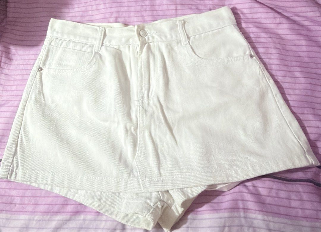 White denim skorts size XXL (Category: Shorts) located in Manila. Submitted by prelovedbynors_ (Listing ID 1470228347, Image 2). Description: - Item: White Denim Skorts - Size: XXL on tag but size 32 inches - Fit: High-waisted with built-in shorts underneath - Details: Front button closure, belt loops, and front pockets - Condition: Shows some yellowing/discoloration near seams and inner folds due to storage - Style: Solid basic piece, perfect fo