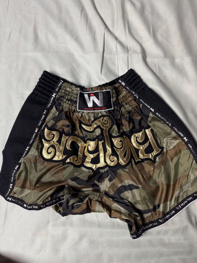 Win Muay Thai Camouflage Shorts Size L (Category: Shorts) located in Manila. Submitted by seangoart (Listing ID 1470316722, Image 1). Description: - Brand: Win Muay Thai - Design: Camouflage pattern with striking gold Thai lettering - Material/Features: Breathable black mesh panels on both sides, comfortable elastic waistband - Size: Large (tag attached) - Condition: Brand new with tag - Best for: Training, sparring, and ring workouts - Shipping 