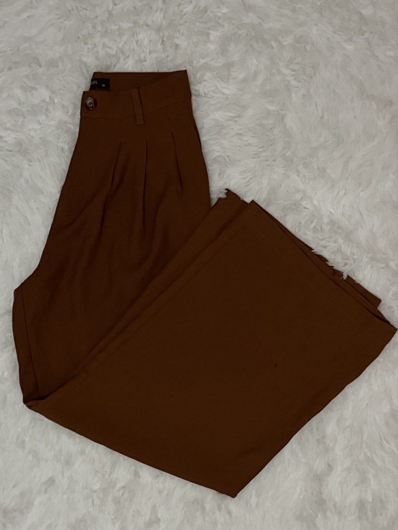 WOMAN Rust Brown Trouser Pants (Category: Other Bottoms) located in Batangas. Submitted by claverialyka (Listing ID 1470196409, Image 3). Description: Color: Rust Brown / Reddish-Brown Style: High-Waisted, Wide-Leg Fit: Relaxed, Flowing Silhouette Waistband: Structured with Belt Loops and Button Closure Design: Tailored Front with Pleated Details Material: Woven Fabric (if confirmed by the clothing tag) Occasion: Casual, Office Wear, or Formal At