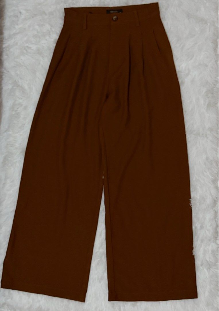 WOMAN Rust Brown Trouser Pants (Category: Other Bottoms) located in Batangas. Submitted by claverialyka (Listing ID 1470196409, Image 2). Description: Color: Rust Brown / Reddish-Brown Style: High-Waisted, Wide-Leg Fit: Relaxed, Flowing Silhouette Waistband: Structured with Belt Loops and Button Closure Design: Tailored Front with Pleated Details Material: Woven Fabric (if confirmed by the clothing tag) Occasion: Casual, Office Wear, or Formal At
