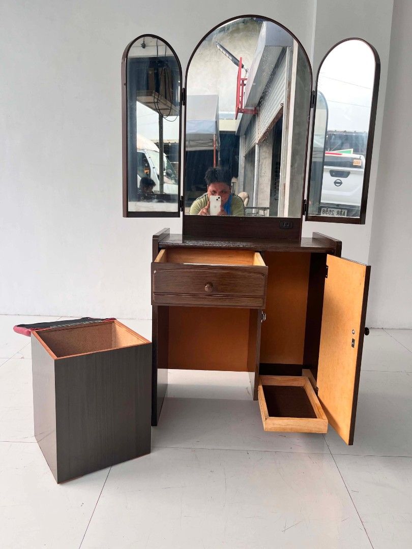 Wooden Vanity Dressing Table with Tri-Fold Mirror and Stool (Category: Tables & Sets) located in Manila. Submitted by roveeeeelen_06 (Listing ID 1470169910, Image 1). Description: - Brown wooden vanity set with a smooth polished finish - Large adjustable tri-fold mirror setup - Includes a matching stool with a comfortable red cushioned top - Ample storage: pull-out drawer on the left and a shelved cabinet on the right - Sturdy structure with clea