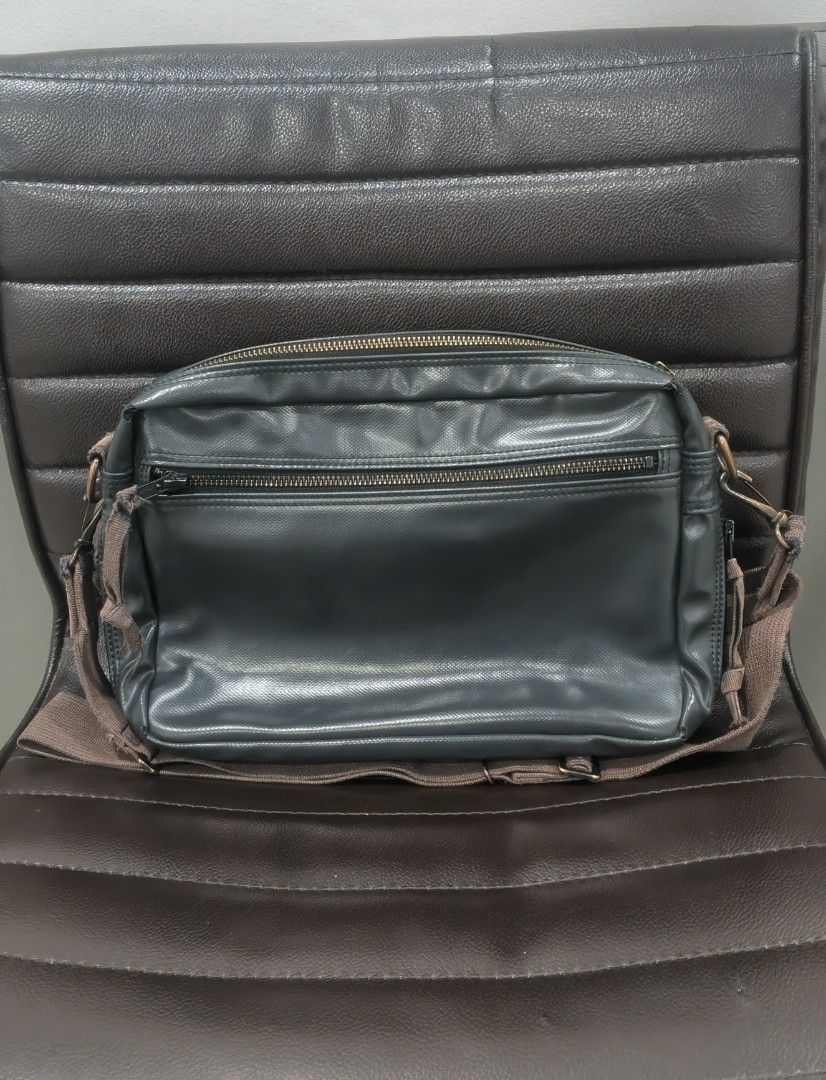 Yoshida & Co (Porter) (Category: Sling Bags) located in Kabacan. Submitted by thriftedsupremacy11 (Listing ID 1470348082, Image 2). Description: The bag is crafted from a distinctive rayon canvas with a PVC coating, giving it a signature glossy finish and a rugged, military-inspired look. It also features the iconic red-and-white cross logo patch in the corner and expandable zipper gussets..