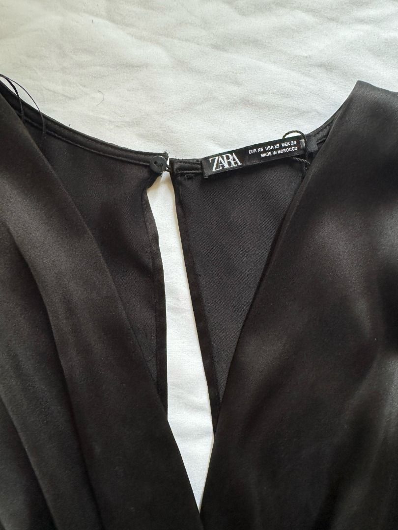 Zara Black Satin Romper Size XS (Category: Rompers) located in Cebu City. Submitted by _t.rix (Listing ID 1470187466, Image 3). Description: - Brand: Zara - Style: Black satin romper with V-neck crossover front - Size: XS (EUR XS, USA XS, MEX 24) - Features: Flare sleeves, attached waist tie with side loop, back button closure with keyhole cutout - Material: Smooth, shiny fabric - Condition: Clean and ready to wear.