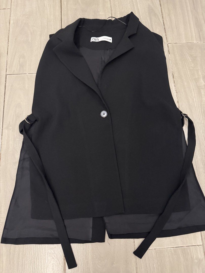 Zara Black Sleeveless Blazer Vest (Category: Sleeveless) located in Taguig. Submitted by sqaumejada (Listing ID 1470154436, Image 1). Description: - Brand: Zara - Style: Sleeveless blazer vest with single-button closure and lapels - Size: XL - Color: Black - Features: Dual side tie straps and a stylish layered sheer fabric panel at the back - Origin: Made in Morocco - Condition: Great piece for layering over tops or dresses.