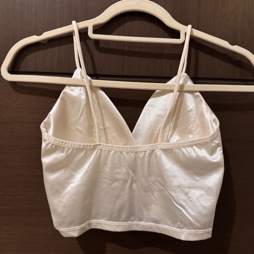 White Satin Crop Top Cami (Category: Sleeveless) located in Quezon City. Submitted by ianne.declutter (Listing ID 1470176731, Image 2). Description: - Brand: Zara TRF - Style: V-neck crop top with thin shoulder straps and criss-cross back - Material: White satin, shiny and smooth texture - Styling tip: Looks amazing paired with a denim jacket - Condition: Excellent.