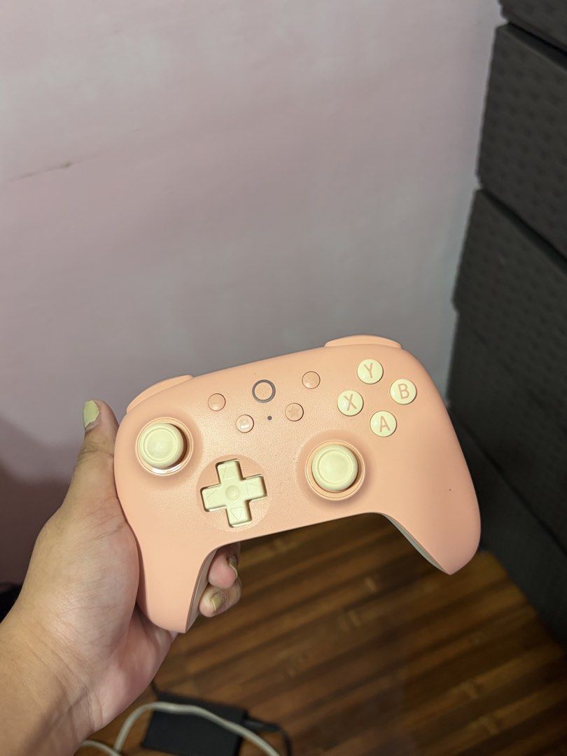 8Bit Peach Pink Wireless Gaming Controller with Cream Buttons (Category: Controllers) located in Cabuyao City. Submitted by madelragas (Listing ID 1470460553, Image 1). Description: - Color: Peach pink with cream d-pad, analog sticks, and face buttons - Layout: Standard ABXY with central function buttons - Connectivity: Wireless for seamless gaming - Design: Ergonomic grip for long, comfortable sessions - Compatibility: Works great with PC and va