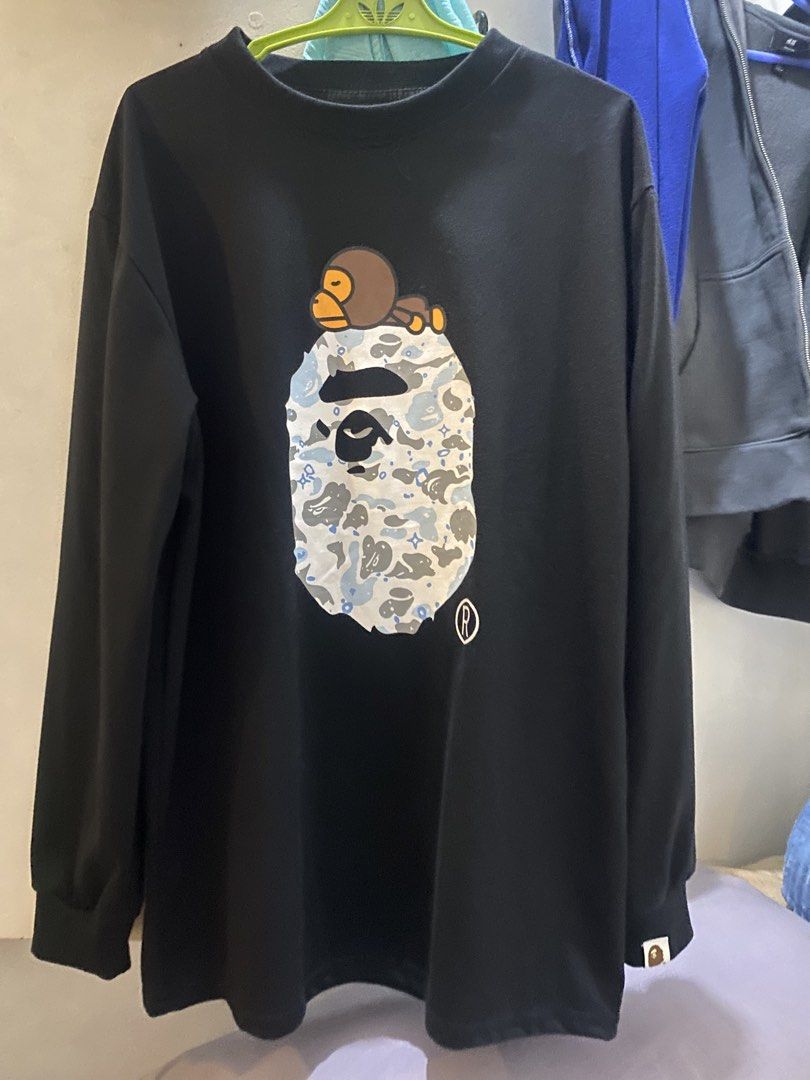 A Bathing Ape Long Sleeve (Category: Hoodies) located in Marikina City. Submitted by ctgccc (Listing ID 1470485559, Image 1). Description: Black long sleeve Size: medium. Used: twice Damages: none Loc: Marikina Large Baby Milo and camo graphic printed right on the front. Neck tape has embossed lettering detail..