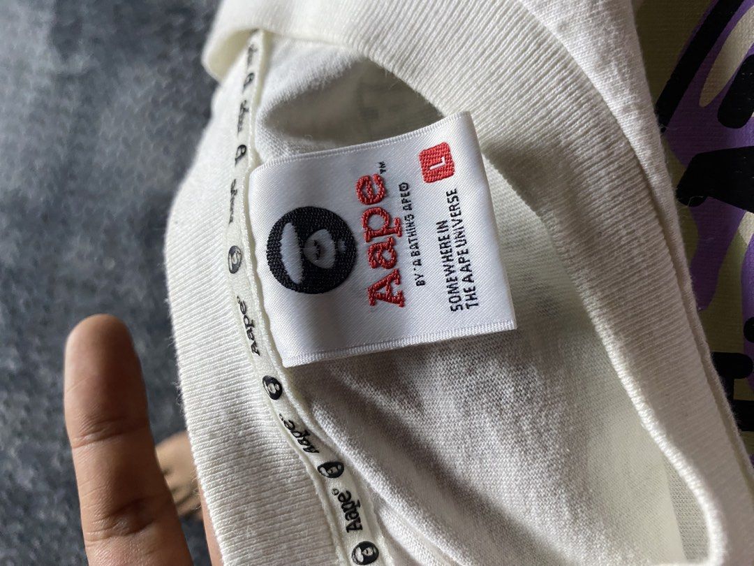 Aape By A Bathing Ape Long Sleeve Tee (Category: Tshirts & Polo Shirts ) located in Olongapo. Submitted by WAVYT (Listing ID 1470552412, Image 3). Description: White long sleeve shirt from Aape by A Bathing Ape. Big circular logo graphic on the chest with purple and green camo print inside. Classic Ape head right in the center. Neck tag inside and sleeve patch logo detail included. Size large printed on the inner collar label. Streetwear piece, c