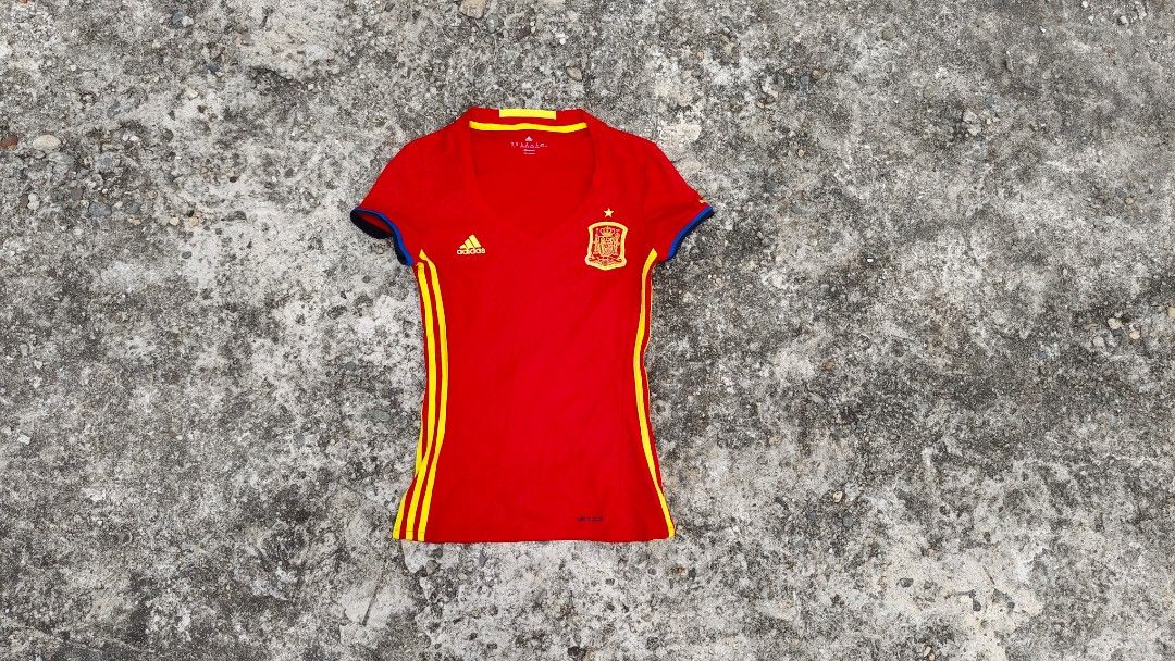 Adidas 2016 Spain Home Jersey (Category: Blouses) located in Mati. Submitted by gsthrift (Listing ID 1470361557, Image 1). Description: This piece is an official Adidas women's home jersey produced for the Spanish national football team's UEFA Euro 2016 campaign. Constructed with Adidas Climacool technology, it features the team's traditional red and yellow palette with subtle triangular jacquard patterns woven into the fabric. The front displays