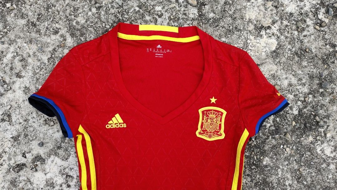 Adidas 2016 Spain Home Jersey (Category: Blouses) located in Mati. Submitted by gsthrift (Listing ID 1470361557, Image 3). Description: This piece is an official Adidas women's home jersey produced for the Spanish national football team's UEFA Euro 2016 campaign. Constructed with Adidas Climacool technology, it features the team's traditional red and yellow palette with subtle triangular jacquard patterns woven into the fabric. The front displays