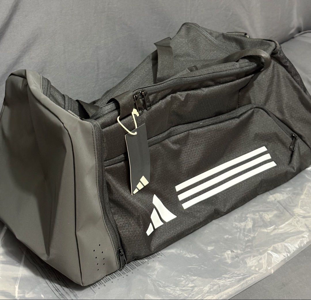 Adidas Essentials 3-Stripes Duffel Bag (Medium) (Category: Sling Bags) located in Manila. Submitted by shoepatos4u (Listing ID 1470416750, Image 2). Description: • Design: Features the iconic Adidas three-stripes branding on a clean black base with white accents. • Comfort: Equipped with an adjustable shoulder strap featuring a movable shoulder pad for easier carrying. • Durability: Built with a durable coated bottom panel to resist wear and tear