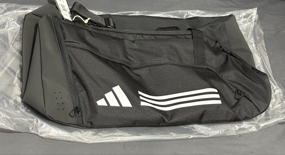 Adidas Essentials 3-Stripes Duffel Bag (Medium) (Category: Sling Bags) located in Manila. Submitted by shoepatos4u (Listing ID 1470416750, Image 1). Description: • Design: Features the iconic Adidas three-stripes branding on a clean black base with white accents. • Comfort: Equipped with an adjustable shoulder strap featuring a movable shoulder pad for easier carrying. • Durability: Built with a durable coated bottom panel to resist wear and tear