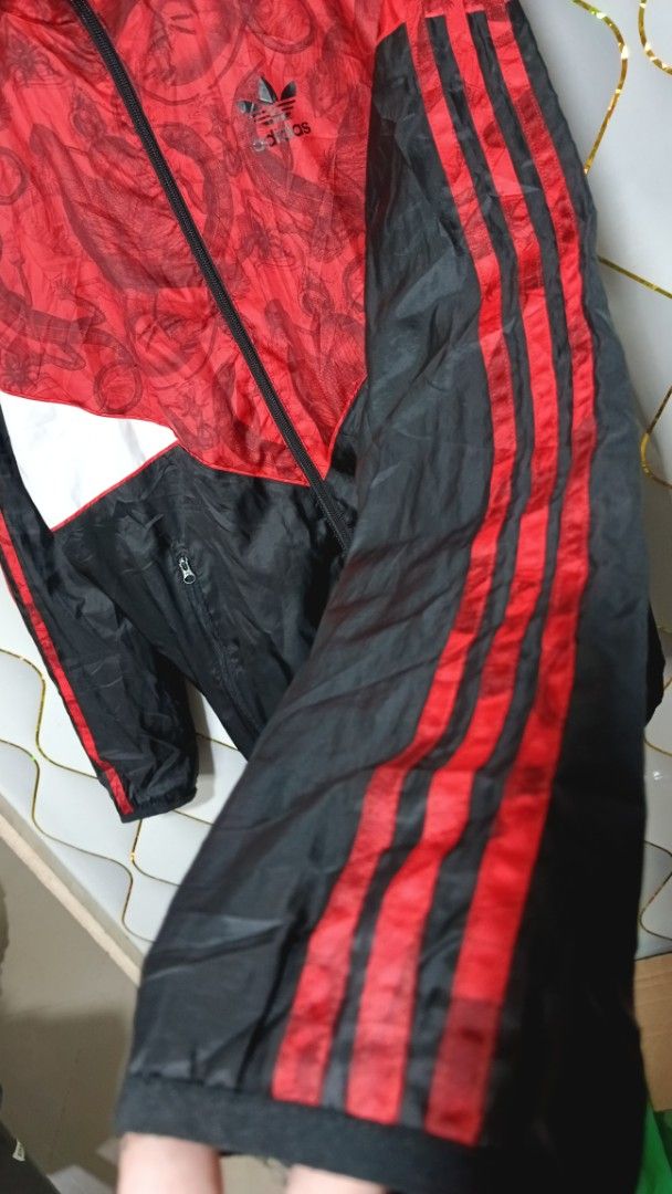 Adidas Red Black White Graphic Windbreaker Jacket (Category: Coats, Jackets and Outerwear) located in Manila. Submitted by zariyah.1986 (Listing ID 1470454805, Image 3). Description: - Brand: Adidas - Style: Hooded windbreaker jacket with full zip closure - Colorway: Red, black, and white with a unique graphic pattern on the top and hood - Details: Red three-stripe branding on sleeves and embroidered trefoil logo on the chest - Lining: Breathable