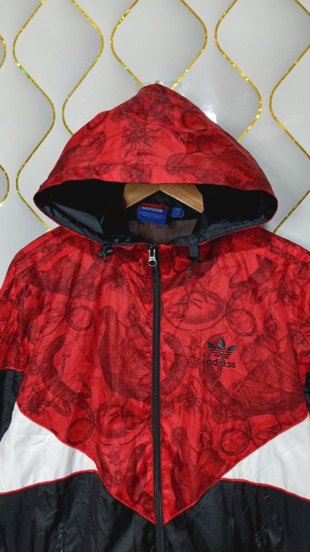 Adidas Red Black White Graphic Windbreaker Jacket (Category: Coats, Jackets and Outerwear) located in Manila. Submitted by zariyah.1986 (Listing ID 1470454805, Image 2). Description: - Brand: Adidas - Style: Hooded windbreaker jacket with full zip closure - Colorway: Red, black, and white with a unique graphic pattern on the top and hood - Details: Red three-stripe branding on sleeves and embroidered trefoil logo on the chest - Lining: Breathable