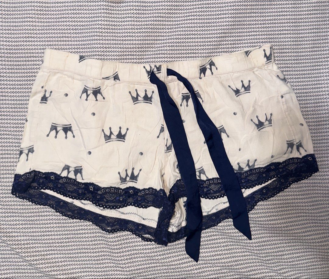 Aerie Crown Print Sleep Shorts (Category: Shorts) located in Santa Ana. Submitted by fatikilla (Listing ID 1470364977, Image 1). Description: - Brand: Aerie - Size: XS - Color/Design: Cream with grey crown print - Details: Dark blue lace trim on hems and matching dark blue satin ribbon drawstring waist - Material/Origin: Made in India, soft and breathable fabric - Condition: Perfect for sleeping, lounging, and relaxing at home.