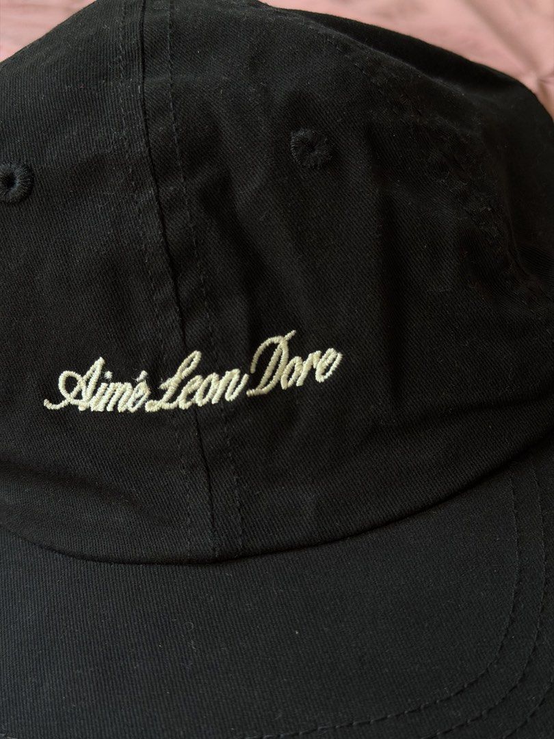 aimé leon dore script logo cap black (Category: Caps & Hats) located in Manila. Submitted by _____car0usell (Listing ID 1470391189, Image 3). Description: - used only once (3.5k from ig shop) - classic black with cream script logo embroidery - adjustable strap closure with metal hardware - clean interior woven brand tag at back seam - with minor sweatband stain from wearing once, can easily be washed.