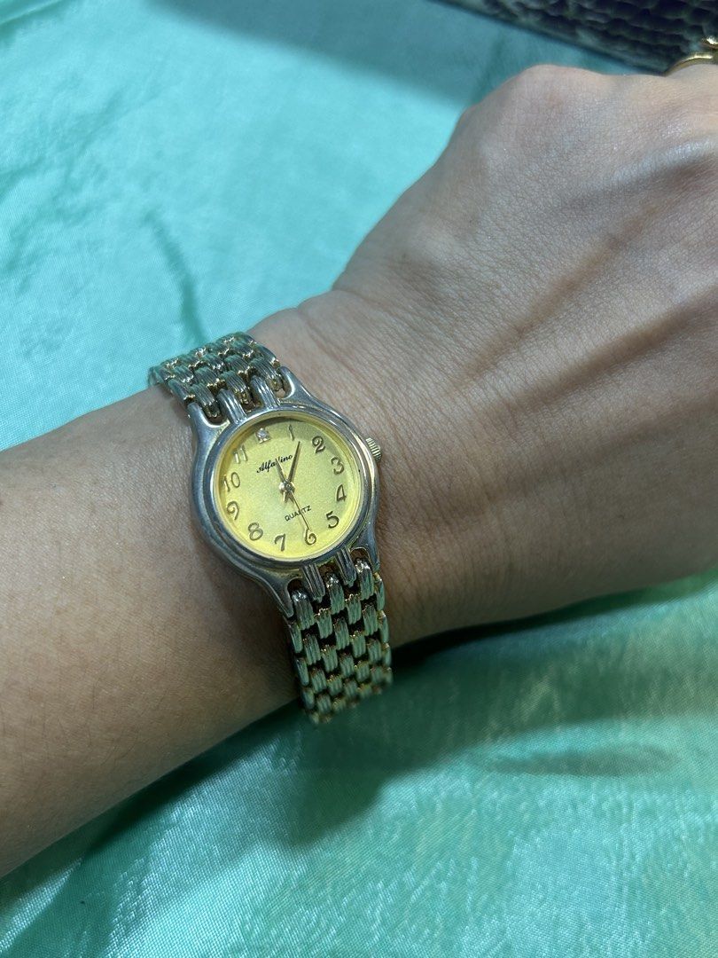 Alfadino Gold Tone Quartz Watch (Category: Women's Watches) located in Cavite. Submitted by mamamia73 (Listing ID 1470530574, Image 2). Description: - Brand/Model: Alfadino vintage quartz watch - Dial: Gold dial with Arabic numerals and a diamond accent at 12 o'clock - Strap: Two-tone textured link bracelet (gold and silver combination) - Back/Movement: Stainless steel back with Japan movement design - Style: Classic vintage timepiece, ideal for 