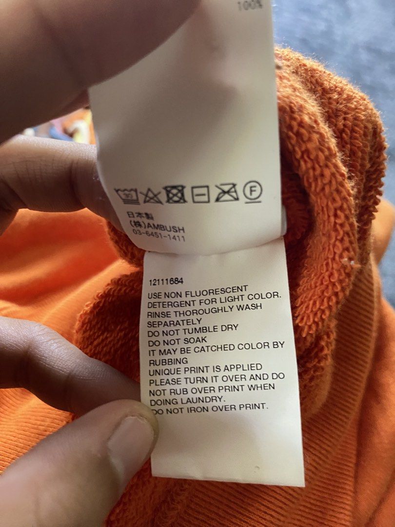 Ambush (Category: Coats, Jackets and Outerwear) located in Olongapo. Submitted by WAVYT (Listing ID 1470552410, Image 3). Description: - Brand: AMBUSH - Color: Bright Orange with multi-colored braided drawstrings and silver aglets - Size: 2 (Medium) - Material: 100% Cotton terry cloth (Made in Japan) - Details: White screenprinted chest logo, front kangaroo pocket - Condition: Interior branding tag and complete care tags attached 23-29.