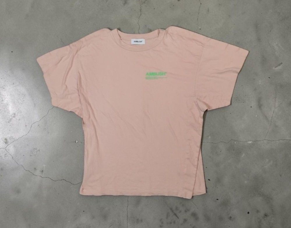 Ambush - Minimal Chest Script Logo - Layered Oversized Tshirt (Category: Shirts) located in Manila. Submitted by grmnts_frmthe_slmz (Listing ID 1470402563, Image 1). Description: AMBUSH short sleeve t-shirt in pale pink. Green logo printed on the upper chest. Crew neck collar with white branded neck tag. Relaxed drop-shoulder fit. Soft cotton fabric, clean finish. Straight hemline with subtle side detail. Ambush - Minimal Chest Script Logo - Laye