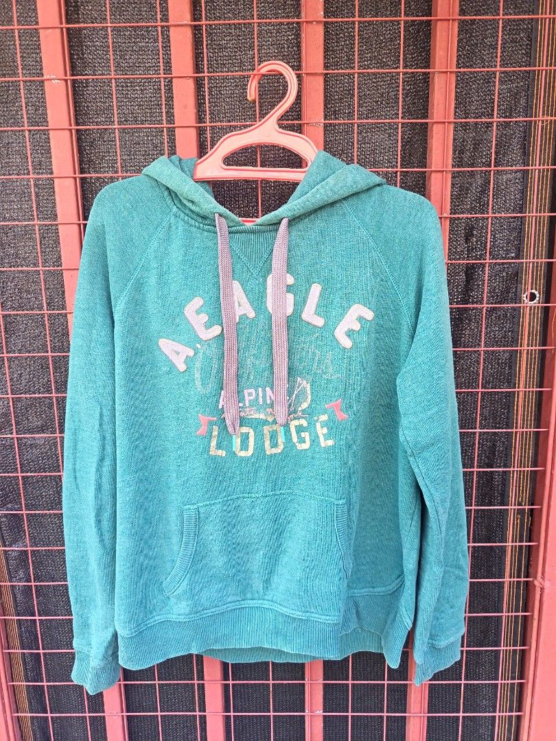 American eagle hoodie (Category: Coats, Jackets and Outerwear) located in Aroroy. Submitted by vin2za06 (Listing ID 1470351903, Image 1). Description: This is a teal or hunter green American Eagle Outfitters "Alpine Lodge" long-sleeve graphic hoodie for women, featuring a kangaroo pocket and drawstring hood..
