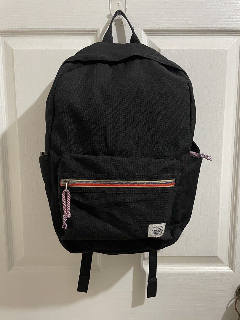 American Tourister Black Backpack (Category: Backpacks) located in Naga. Submitted by thriftboss88 (Listing ID 1470481215, Image 1). Description: - Brand: American Tourister - Color: Classic Black - Material: Durable canvas - Front zipper pocket with stylish red, white, and blue stripe detail and braided cord pull - Two convenient side slip pockets for water bottles or essentials - Adjustable, padded black shoulder straps for all-day comfort - St