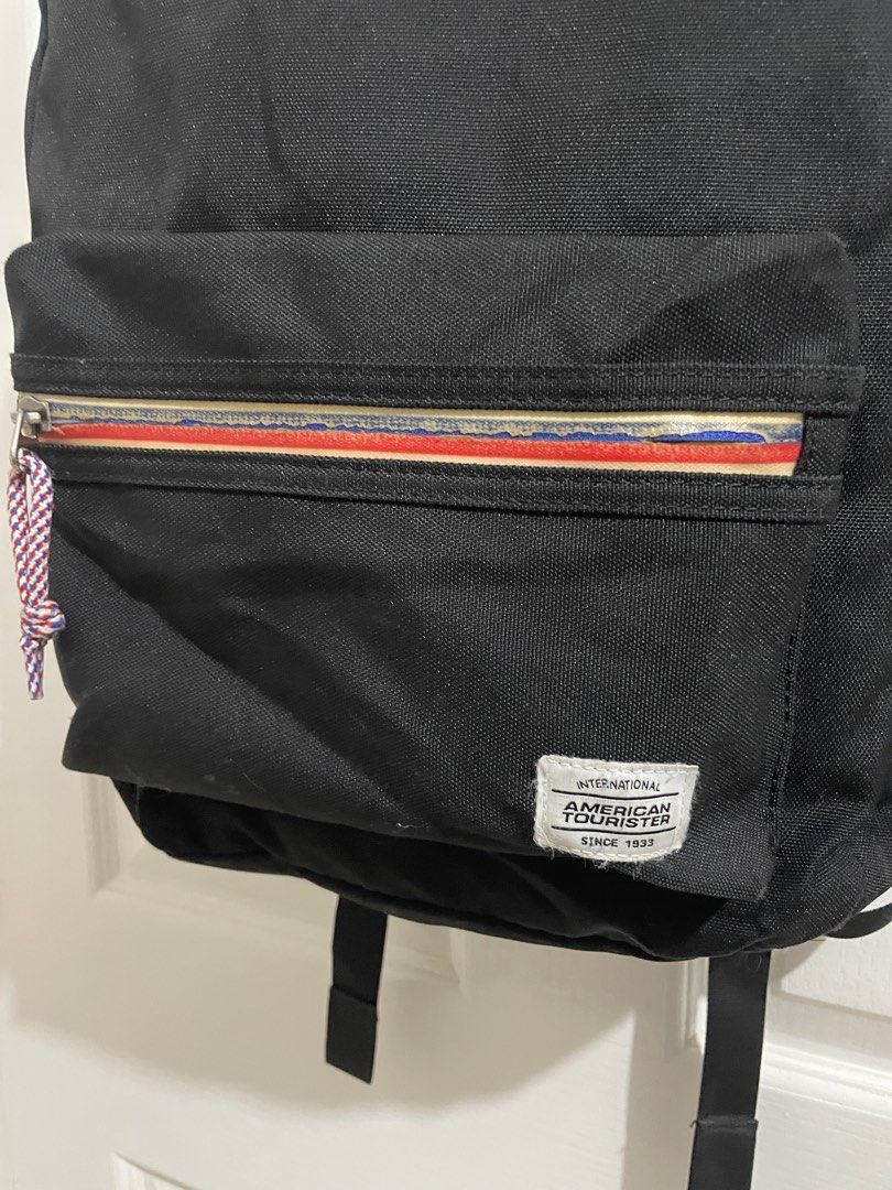 American Tourister Black Backpack (Category: Backpacks) located in Naga. Submitted by thriftboss88 (Listing ID 1470481215, Image 2). Description: - Brand: American Tourister - Color: Classic Black - Material: Durable canvas - Front zipper pocket with stylish red, white, and blue stripe detail and braided cord pull - Two convenient side slip pockets for water bottles or essentials - Adjustable, padded black shoulder straps for all-day comfort - St