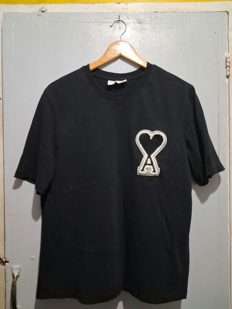 Ami Paris Black Heart Patch T-Shirt (Category: Tshirts & Polo Shirts ) located in General Santos City (Dadiangas). Submitted by nikkomendez31 (Listing ID 1470420226, Image 1). Description: - Brand: Ami Paris - Color: Solid black - Material: Soft, premium cotton - Fit: Regular fit, short sleeves, classic crew neck - Details: Large white heart patch logo on left chest, small embroidered logo lettering on back collar - Condition: Very good.