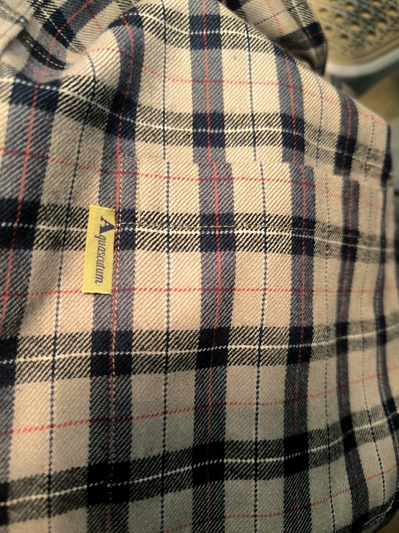 Aquascutum Plaid Button-Down Shirt Size L (Category: Tshirts & Polo Shirts ) located in Caloocan City. Submitted by wan_l_as (Listing ID 1470392544, Image 3). Description: - Brand: Aquascutum - Style: Long sleeve button-down shirt - Pattern: Classic check (cream, navy, and red tones) - Size: Large - Details: Chest pocket with yellow brand tag, button cuffs - Condition: Clean, sharp collar and hems.