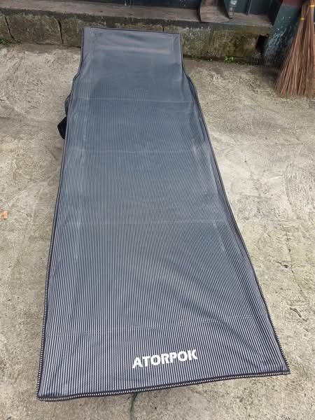 ATORPOK portable folding camping cot (Category: Outdoor Furniture) located in Sablan. Submitted by gongonshelley12 (Listing ID 1470463781, Image 2). Description: ATORPOK portable folding camping cot with a black fabric deck and a tan/beige X-frame support structure. Heavy Duty and Quality. Mahal din ng market value nito .
