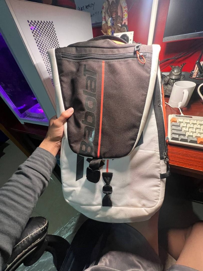 Babolat Strike Tennis Racquet Holder Backpack (Category: Racket and Ball Sports) located in Baguio. Submitted by carlbenta (Listing ID 1470495408, Image 3). Description: - Brand: Babolat - Colorway: White, Black, and Orange - Design: High-capacity, flexible design engineered in France - Straps: Padded, adjustable backpack straps featuring Babolat and Strike branding - Compartments: Secure zippered compartments for gear and racquets - Condition: C