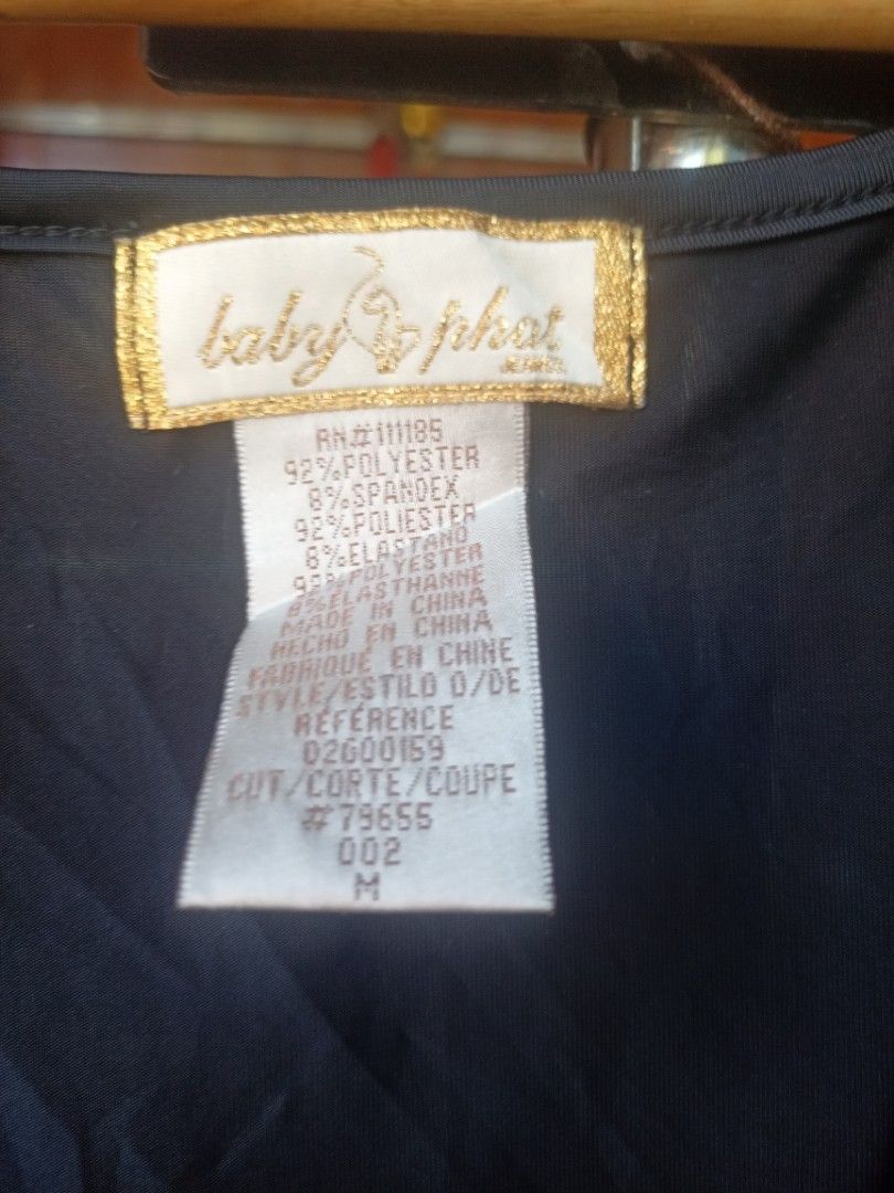Baby Phat Black Ruched Dress Medium (Category: Dresses) located in Cavite. Submitted by ronniel0943882 (Listing ID 1470409381, Image 2). Description: - Brand: Baby Phat - Color: Black - Size: Medium - Material: 92% polyester, 8% spandex (stretchable and comfortable) - Design: Deep V-neckline with gathered front ruching - Details: Adjustable string ties with chic gold hardware beads - Condition: Good, with a small stitched repair on the shoulder f