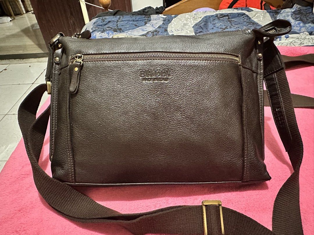 Bally Dark Brown Leather Crossbody Bag (Category: Luxury Bags & Wallets) located in Quezon City. Submitted by pongoy (Listing ID 1470392755, Image 1). Description: - Brand: Bally - Origin: Made in Italy - Material: Premium dark brown grained leather with silver-tone hardware - Strap: Adjustable canvas strap - Storage: Deep main compartment and convenient front zippered pocket - Condition: Clean interior, excellent structure, durable for everyday 