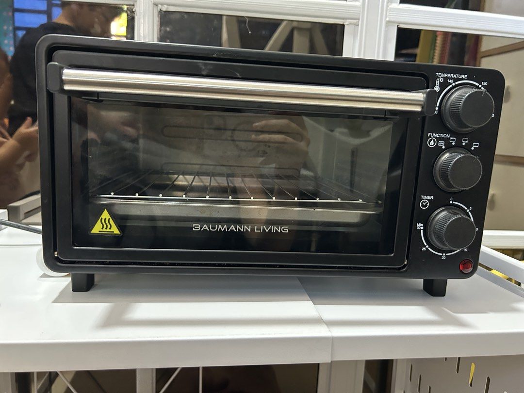 Baumann Living Oven Toaster (Category: Ovens & Toasters) located in Cavite. Submitted by am0602 (Listing ID 1470351339, Image 1). Description: Black Baumann Living toaster oven with stainless steel handle. Temperature knob goes up to 230 degrees Celsius. Function selector and timer dial up to 30 minutes. Includes wire rack and baking tray. Interior and tray show some food stains and grease marks from previous cooking sessions. Glass door with cle