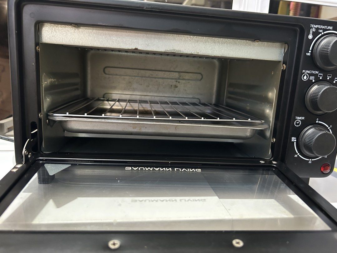 Baumann Living Oven Toaster (Category: Ovens & Toasters) located in Cavite. Submitted by am0602 (Listing ID 1470351339, Image 2). Description: Black Baumann Living toaster oven with stainless steel handle. Temperature knob goes up to 230 degrees Celsius. Function selector and timer dial up to 30 minutes. Includes wire rack and baking tray. Interior and tray show some food stains and grease marks from previous cooking sessions. Glass door with cle