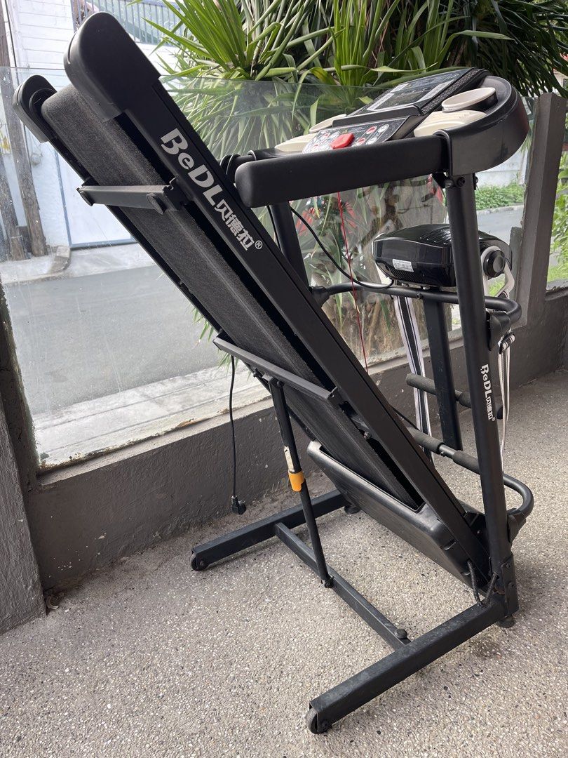 BeDL Folding Electric Treadmill (Category: Cardio & Fitness Machines) located in Paranaque City. Submitted by cheskadejon (Listing ID 1470357001, Image 2). Description: - Brand/Model: BeDL motorized treadmill - Color: Black and orange - Features: Digital display panel, built-in cup holders, and safety key included - Convenience: Folds upright easily for space-saving storage - Condition: Fully intact structure with minor dust from storage - Ideal 