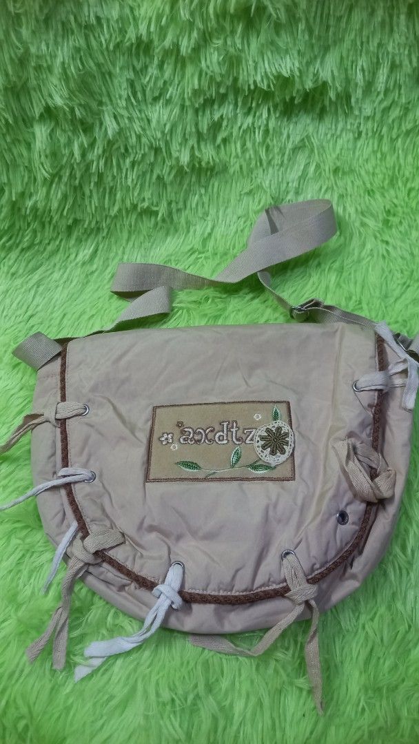 Beige Shoulder Bag with Floral Patch and Drawstrings (Category: Shoulder Bags) located in Manila. Submitted by twinklelyn03 (Listing ID 1470409285, Image 1). Description: - Material: Durable beige nylon fabric - Design: Front flap with floral embroidery, fabric patch, and white tie-string details - Interior: Smooth fabric lining with a handy inner slip pocket - Closure: Secure velcro front closure - Strap: Adjustable shoulder strap for comfortabl