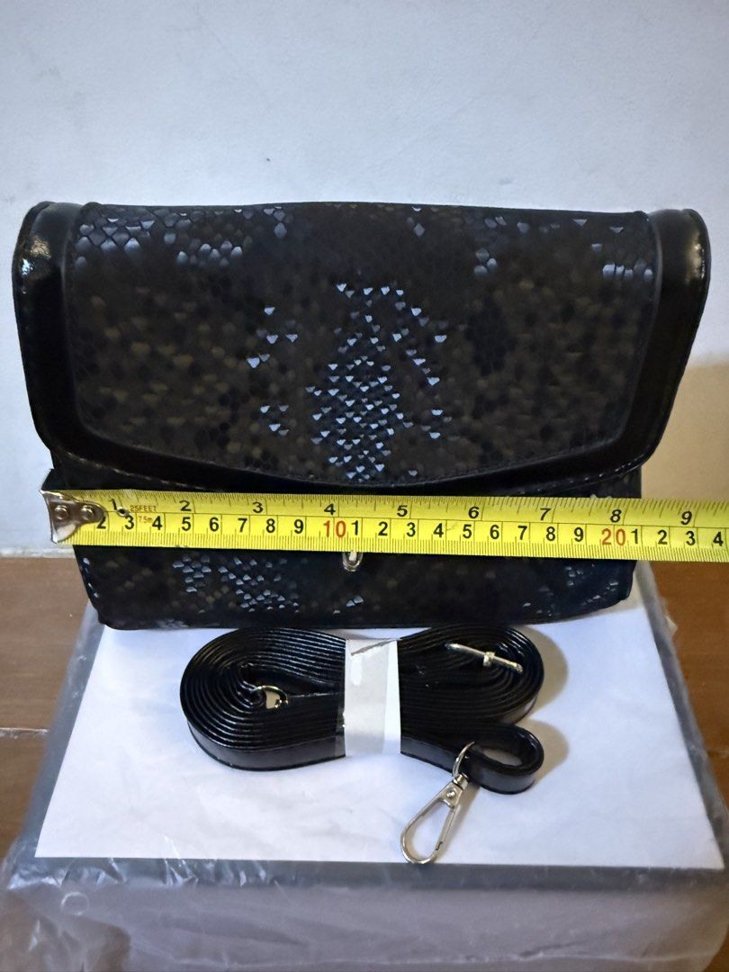 Black snakeskin pattern bag with strap (Category: Cross-body Bags) located in Bulacan. Submitted by emjay_17 (Listing ID 1470410672, Image 3). Description: - Condition: Brand new, never used and super clean inside - Design: Chic black snakeskin pattern with a secure flap closure and metal lock - Size: Compact dimensions, roughly 21cm across and 15cm tall - Interior: Stylish chevron-pattern fabric lining with a convenient middle zippered pocket - 