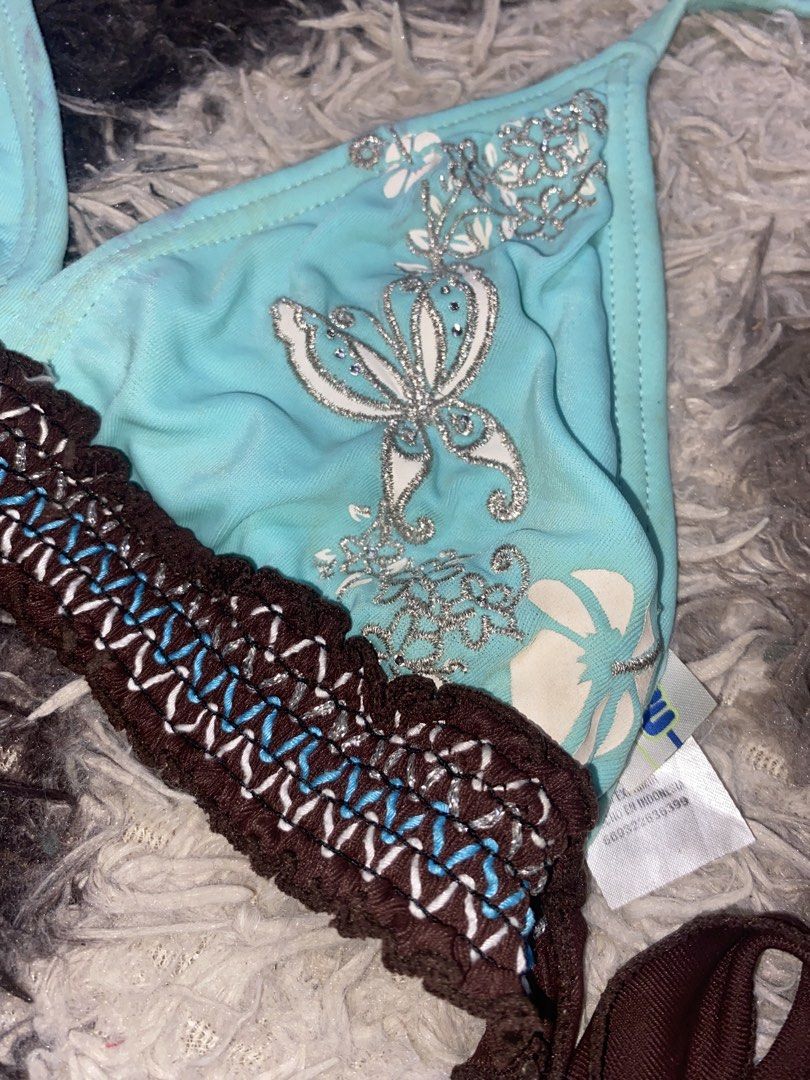Blue Butterfly Halter (Category: Bikinis & Swimsuits) located in Caloocan City. Submitted by remythrift (Listing ID 1470350456, Image 3). Description: - Style: Halter bikini top - Color/Design: Light blue with white hibiscus prints and silver butterfly graphic on right cup - Details: Brown braided underband and contrast stitching - Fit: Adjustable neck and back ties.