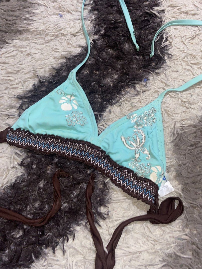 Blue Butterfly Halter (Category: Bikinis & Swimsuits) located in Caloocan City. Submitted by remythrift (Listing ID 1470350456, Image 2). Description: - Style: Halter bikini top - Color/Design: Light blue with white hibiscus prints and silver butterfly graphic on right cup - Details: Brown braided underband and contrast stitching - Fit: Adjustable neck and back ties.