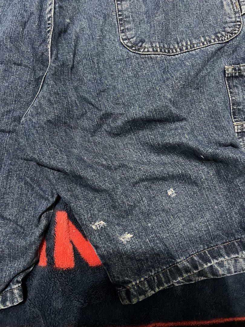 Blue Denim Cargo Shorts (Category: Shorts) located in Tanza. Submitted by 1954_street (Listing ID 1470378945, Image 3). Description: WRANGLER CARPENTER JORTS 38 waist 23 length 13 leg opening minor tattered holes 500 - Style: Classic skater / workwear fit - Color/Material: Blue denim - Features: Multiple utility pockets, regular belt loops, and button closure - Condition: Good with minor fraying and small distress marks near the hem as pictured.