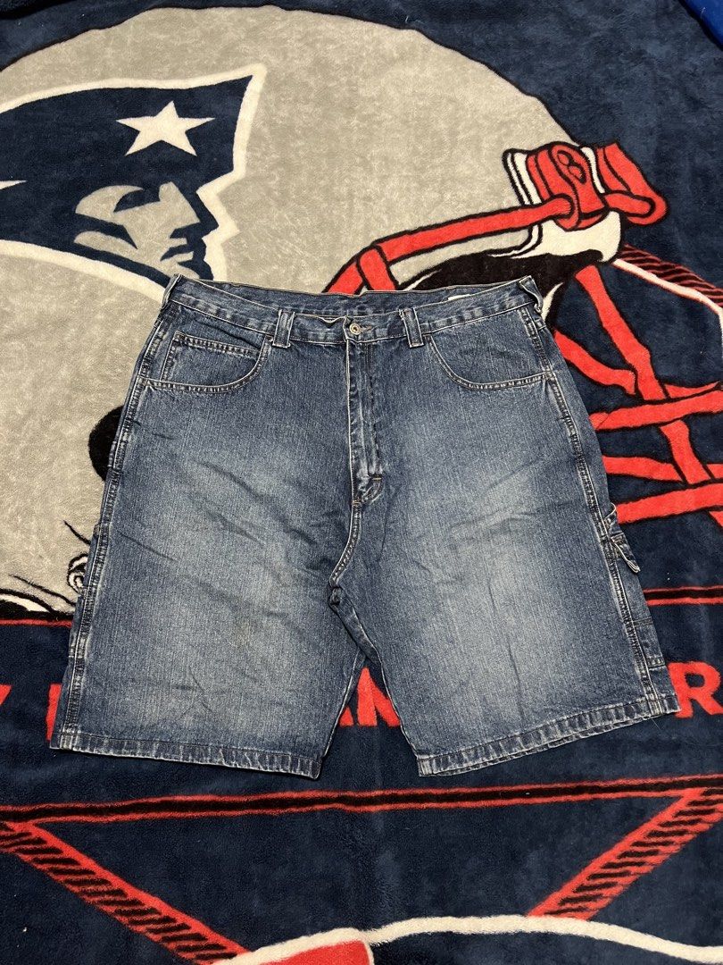 Blue Denim Cargo Shorts (Category: Shorts) located in Tanza. Submitted by 1954_street (Listing ID 1470378945, Image 2). Description: WRANGLER CARPENTER JORTS 38 waist 23 length 13 leg opening minor tattered holes 500 - Style: Classic skater / workwear fit - Color/Material: Blue denim - Features: Multiple utility pockets, regular belt loops, and button closure - Condition: Good with minor fraying and small distress marks near the hem as pictured.